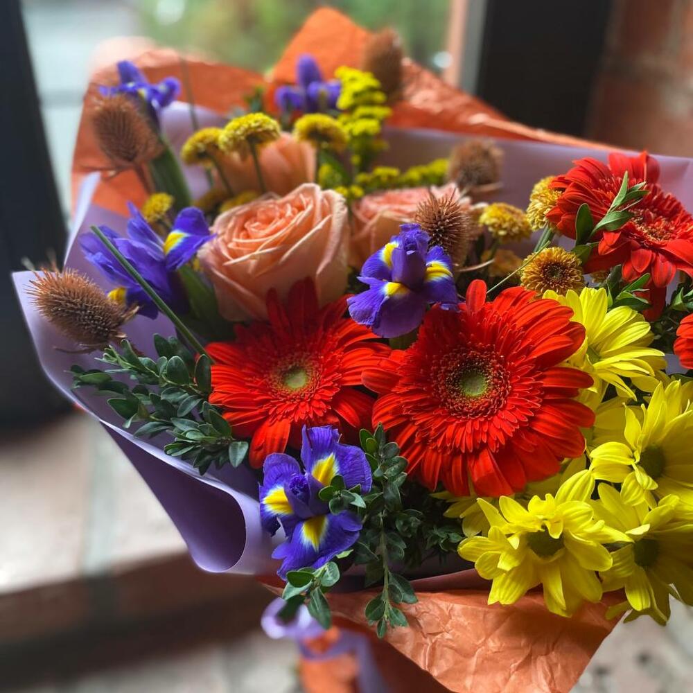 Букет из гербер, ирисов, кустовой хризантемы, пионовидных роз, самшита и эрингиума в стильной упаковке 